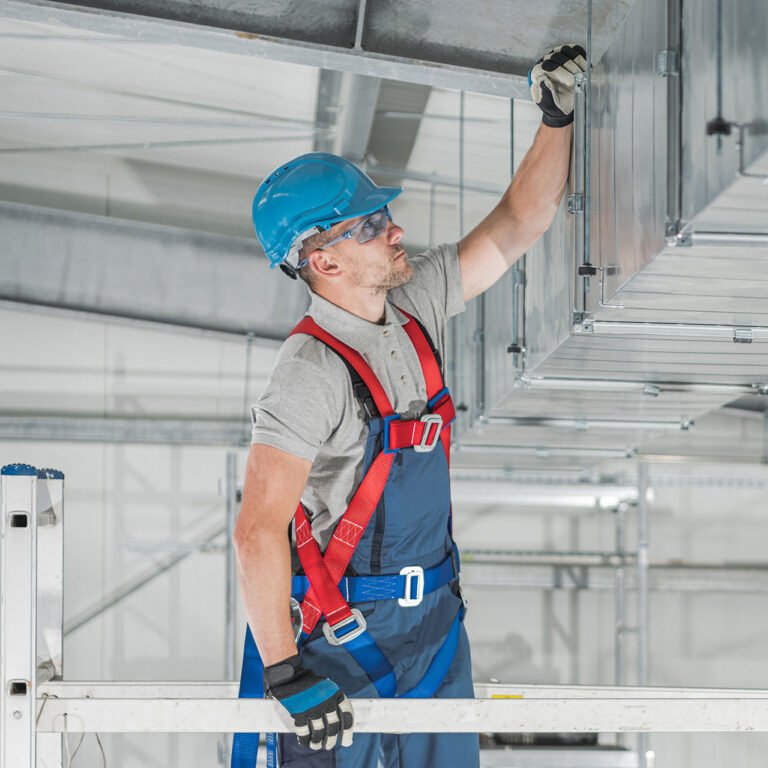 Commercial HVAC Systems Installation Inside the Warehouse Performed by Caucasian Heating and Cooling Technician in His 40s.